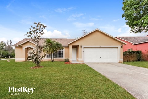 a beige house with a white garage door and a lawn
