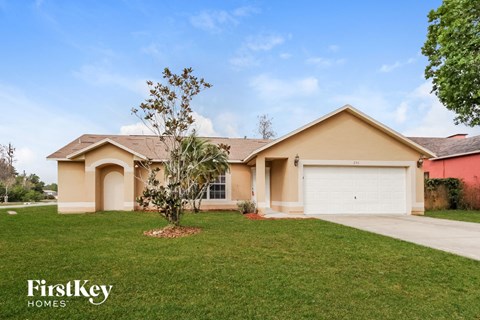 a beige house with a garage and a green lawn