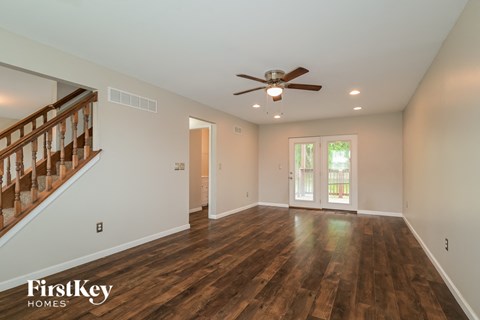A spacious room with wooden floors and a ceiling fan.