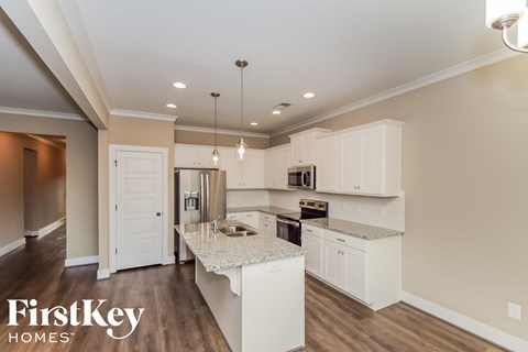 a kitchen with white cabinets and a marble counter top