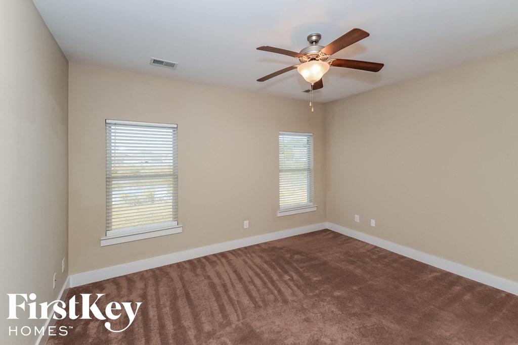 an empty room with a ceiling fan and two windows
