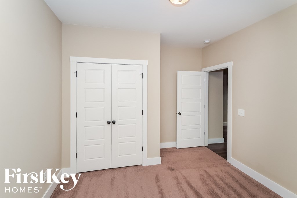 a bedroom with two closets and a door to a hallway with a door open