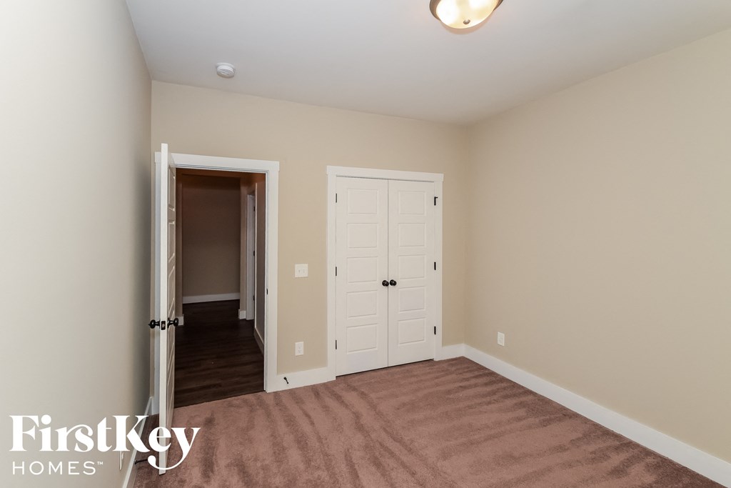 a bedroom with a carpeted floor and a door to a closet