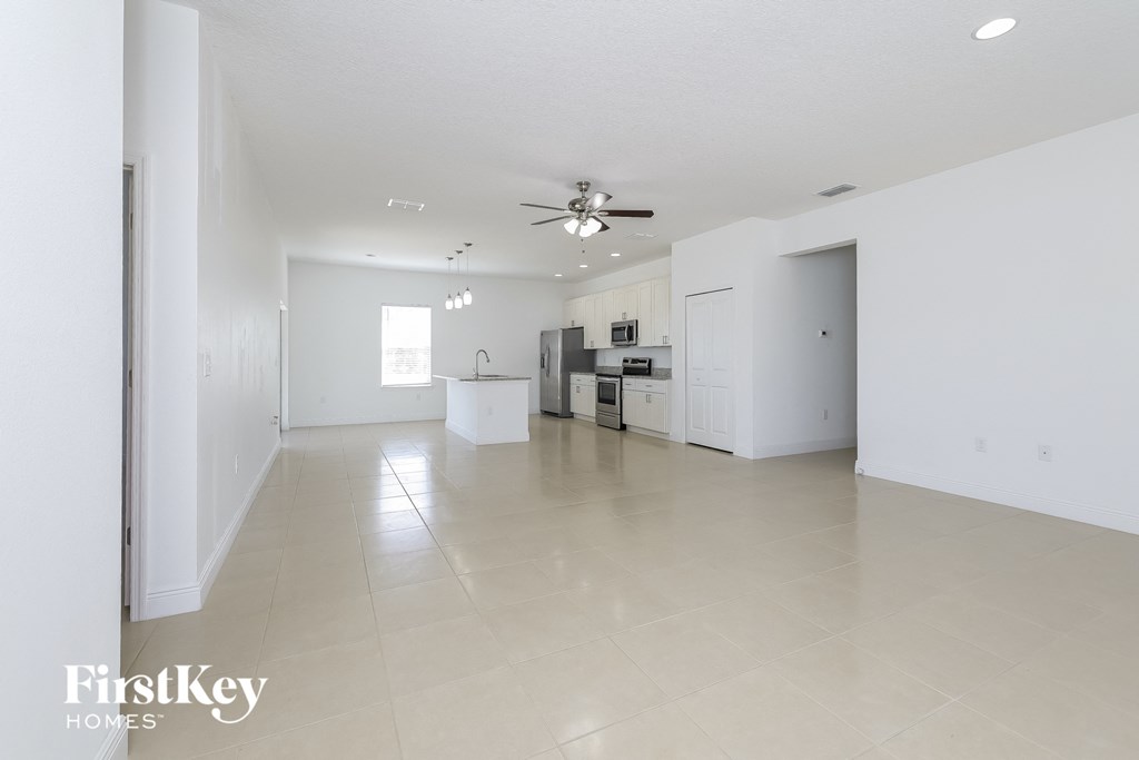 an empty living room and kitchen with white walls and tile floors