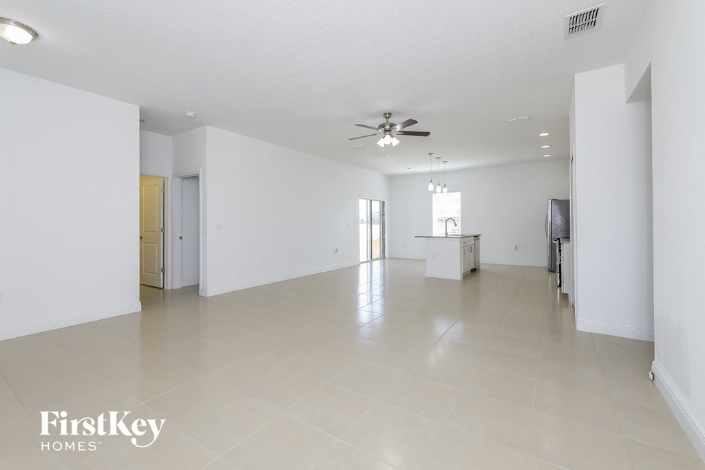 an empty living room with white walls and a ceiling fan