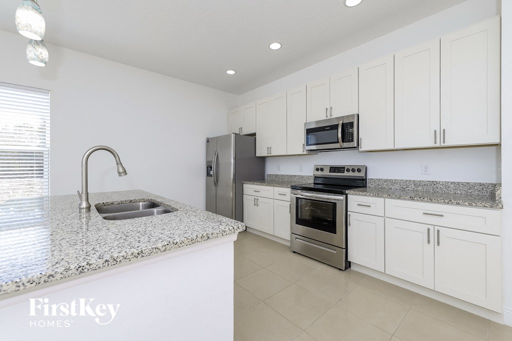 a white kitchen with granite counter tops and stainless steel appliances