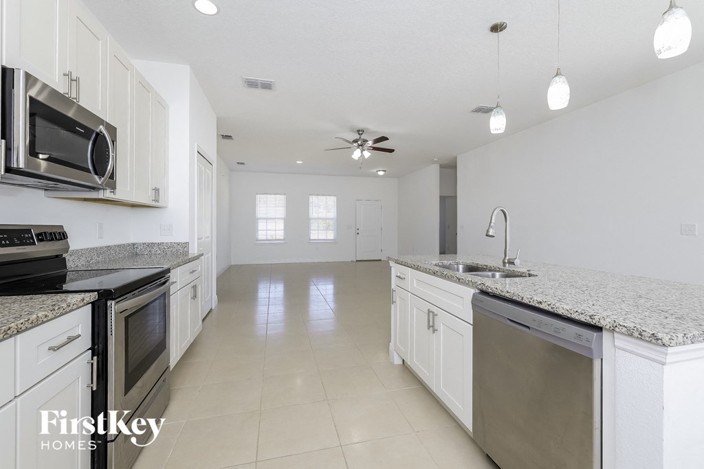 a kitchen with white cabinets and granite counter tops and stainless steel appliances
