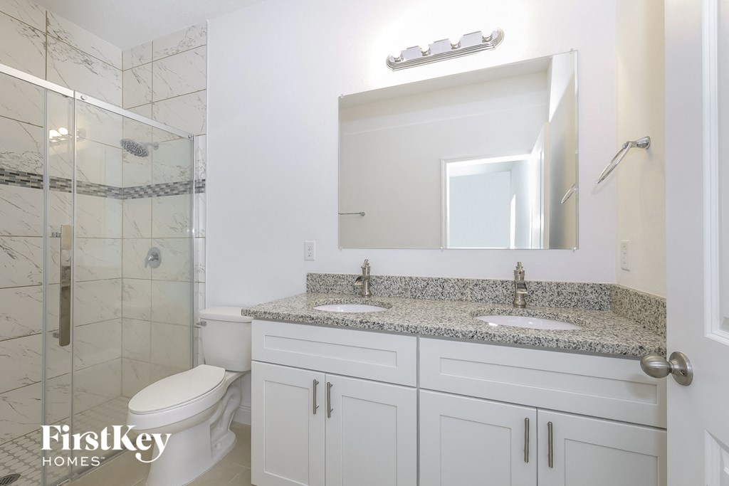 a bathroom with two sinks and a shower and a toilet
