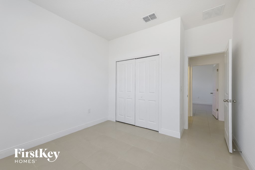 an empty room with a white door and a hallway with a door to a closet