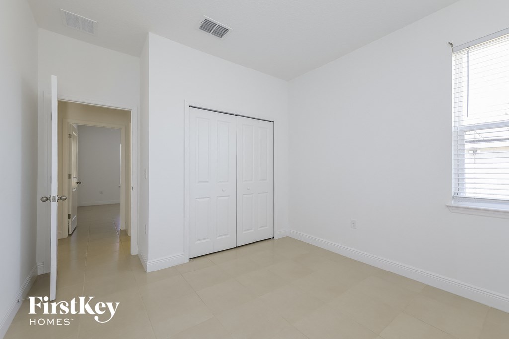 a bedroom with white walls and a white door and a tiled floor