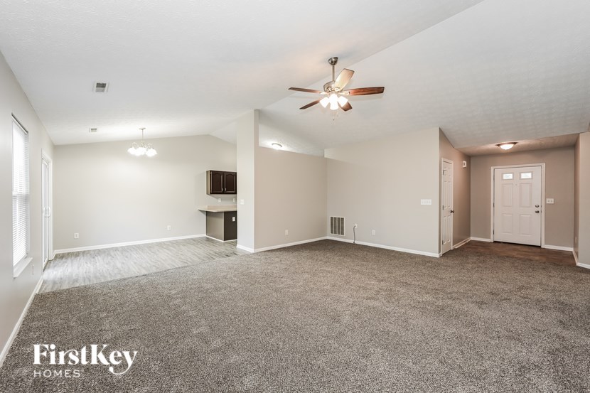 A spacious room with a ceiling fan and carpeted floor.