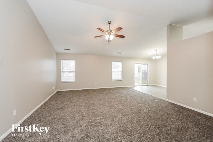 A spacious room with a ceiling fan and carpeted floor.