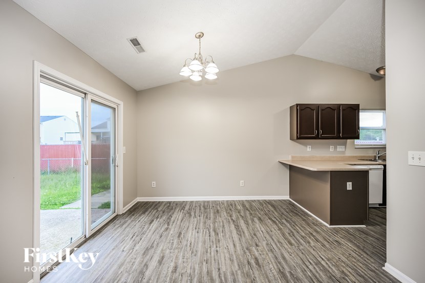 A room with a kitchenette and a sliding glass door.