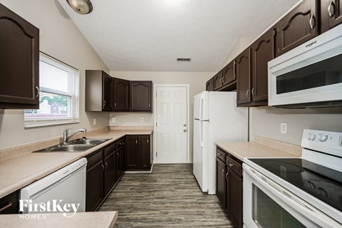 A kitchen with brown cabinets and white appliances.