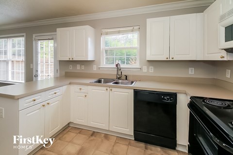 A kitchen with white cabinets and black appliances.