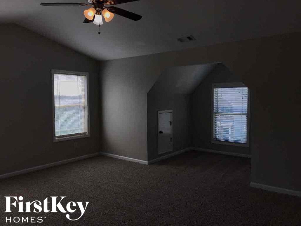 A room with a ceiling fan and two windows.