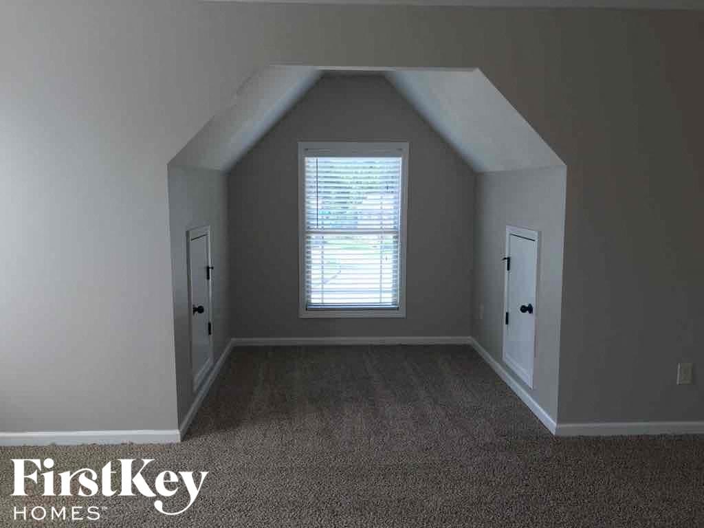 A room with a carpeted floor and a window with blinds.