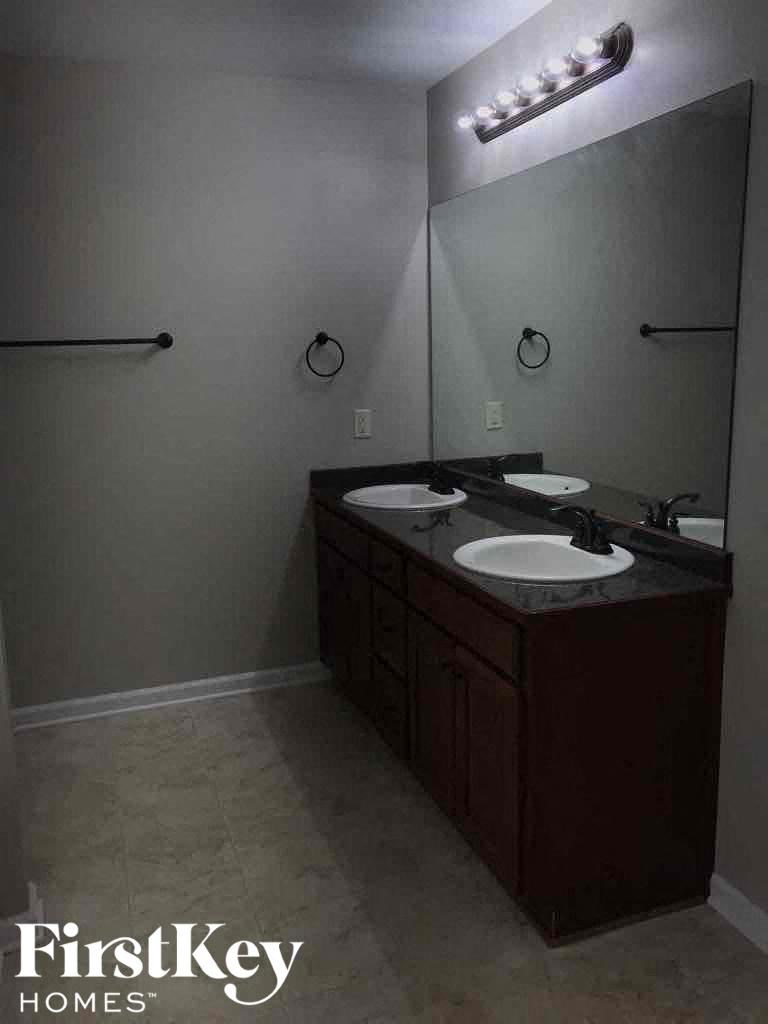 A bathroom with a double sink vanity and a mirror above it.