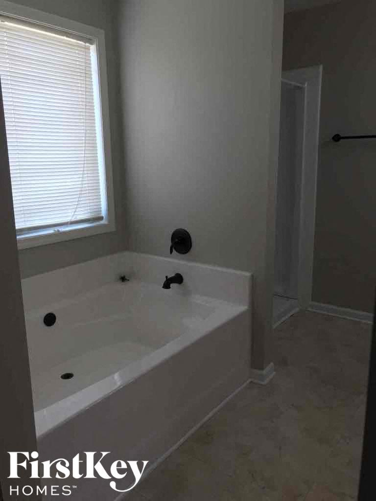 A white bathtub with a window above it in a bathroom.