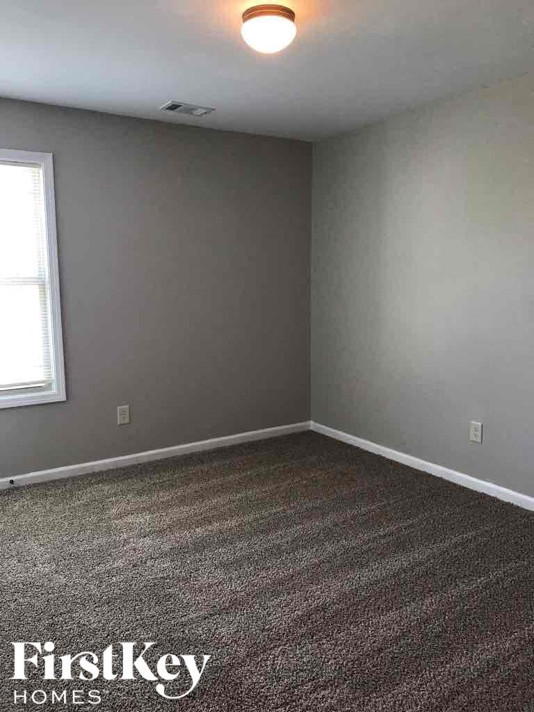 A room with a grey carpet and a window.