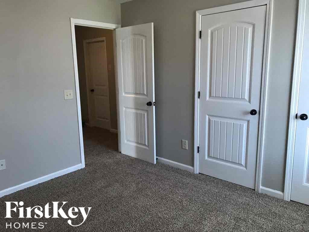 A room with three doors and a carpeted floor.