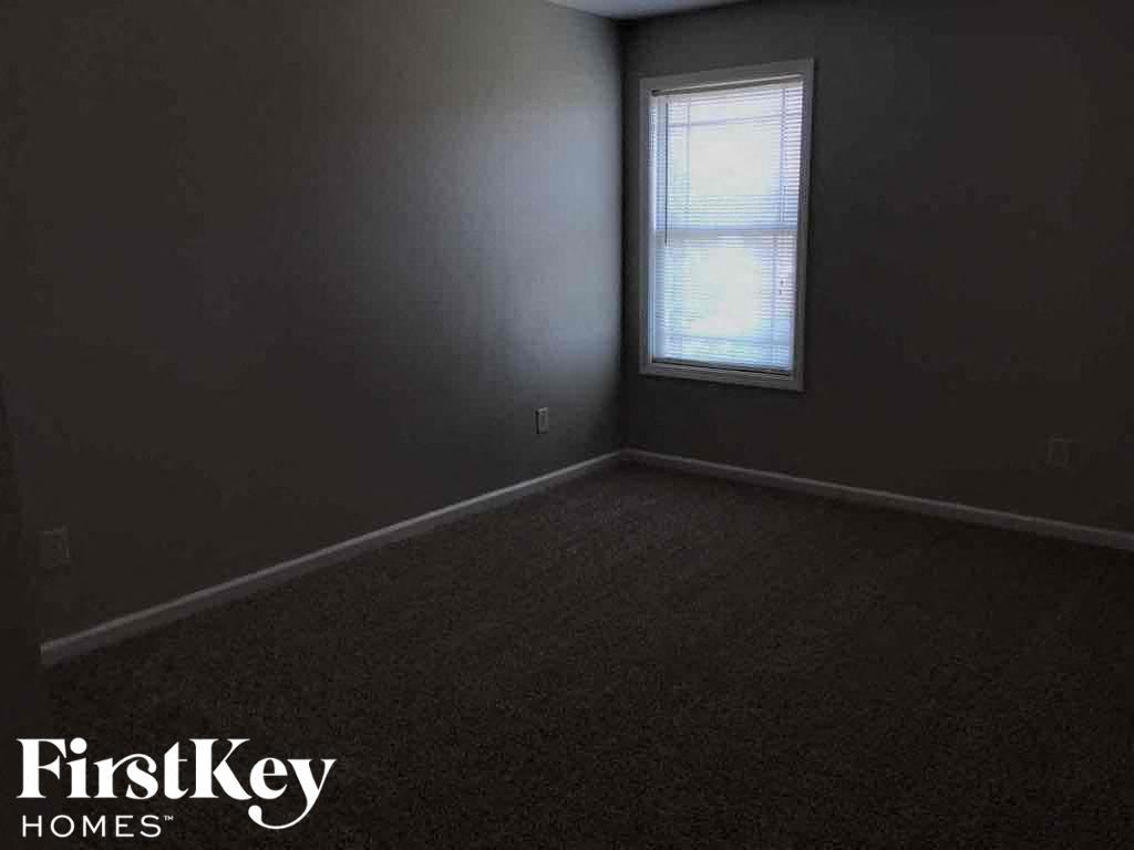 A room with a window and a carpeted floor.