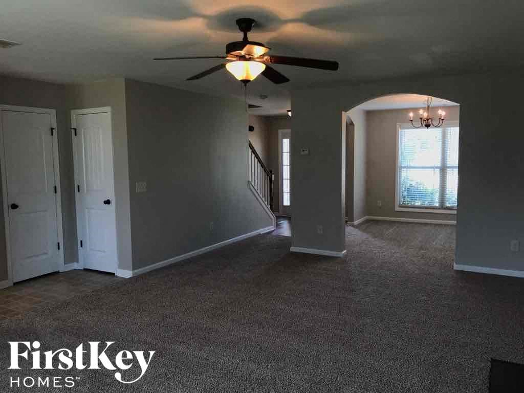 A spacious room with a carpeted floor and a ceiling fan.