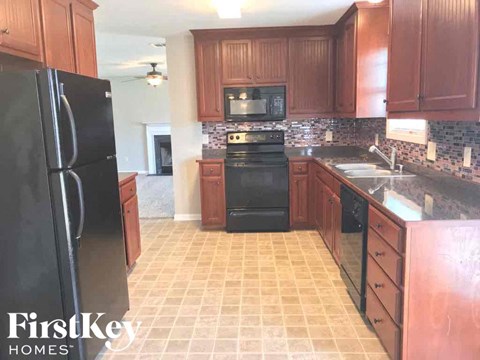 A kitchen with wooden cabinets and a black fridge.