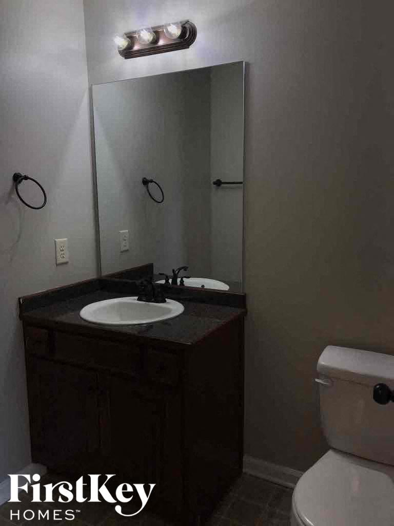 A bathroom with a sink, toilet and mirror.
