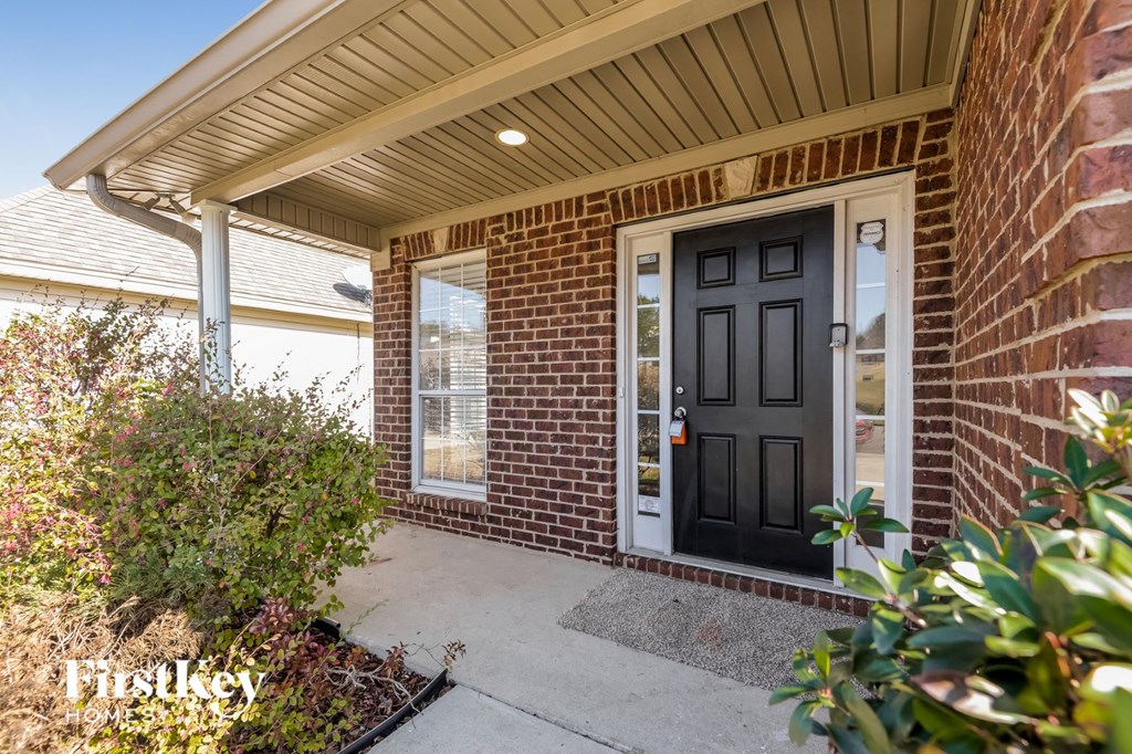 the front porch of a brick house with a black door