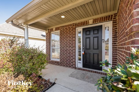 the front porch of a brick house with a black door