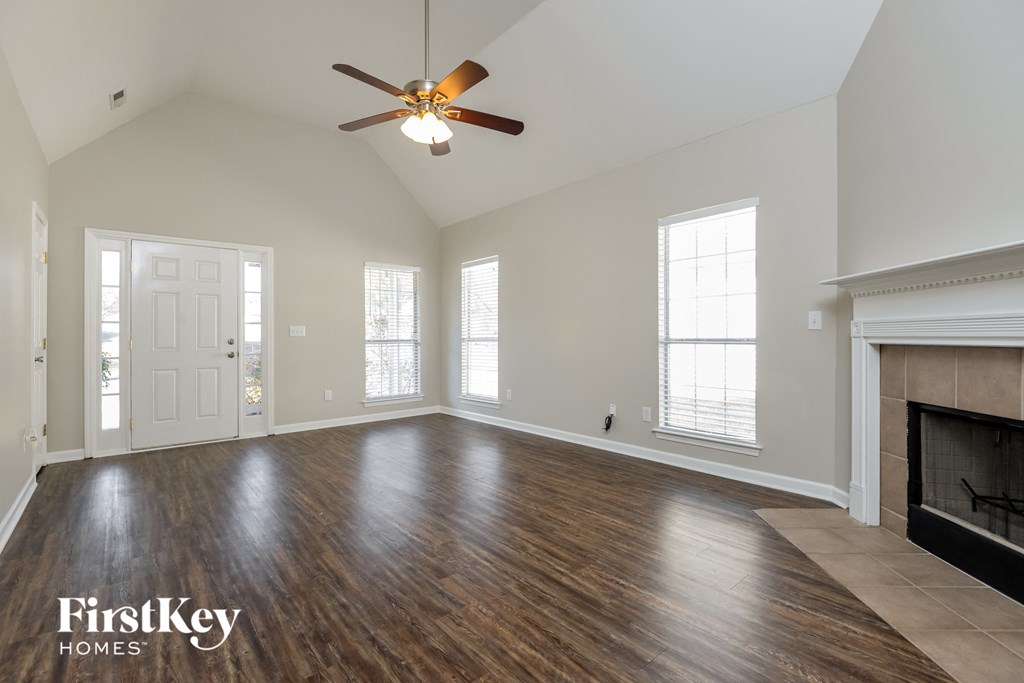 an empty living room with a ceiling fan and a fireplace