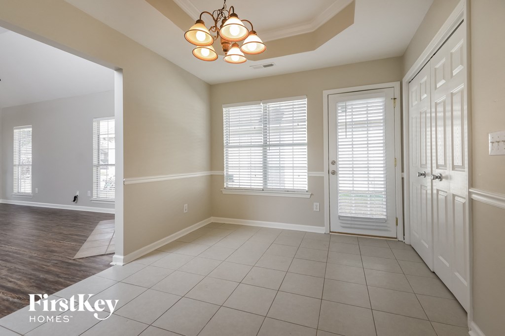 an empty dining room with a white door and a chandelier