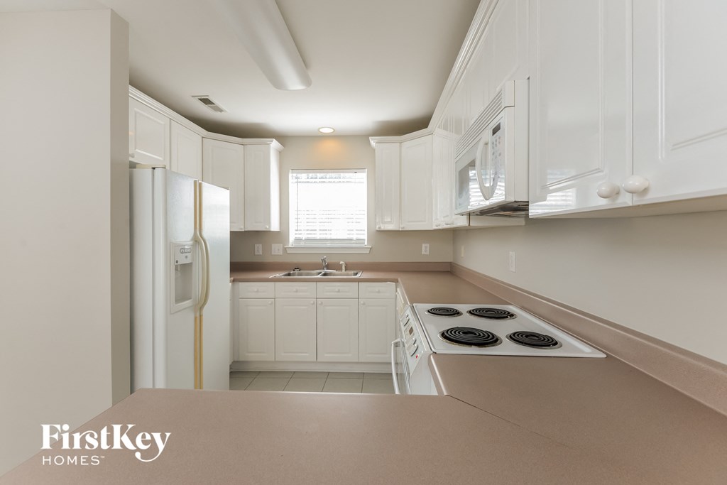 a white kitchen with white cabinets and a white refrigerator