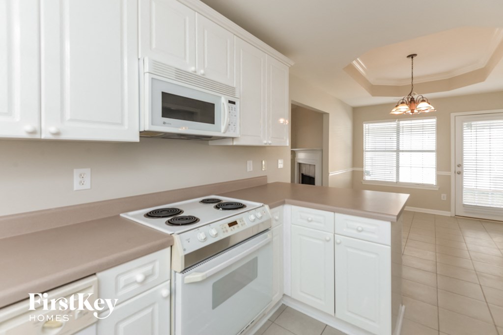 a kitchen with white cabinets and a stove and a microwave