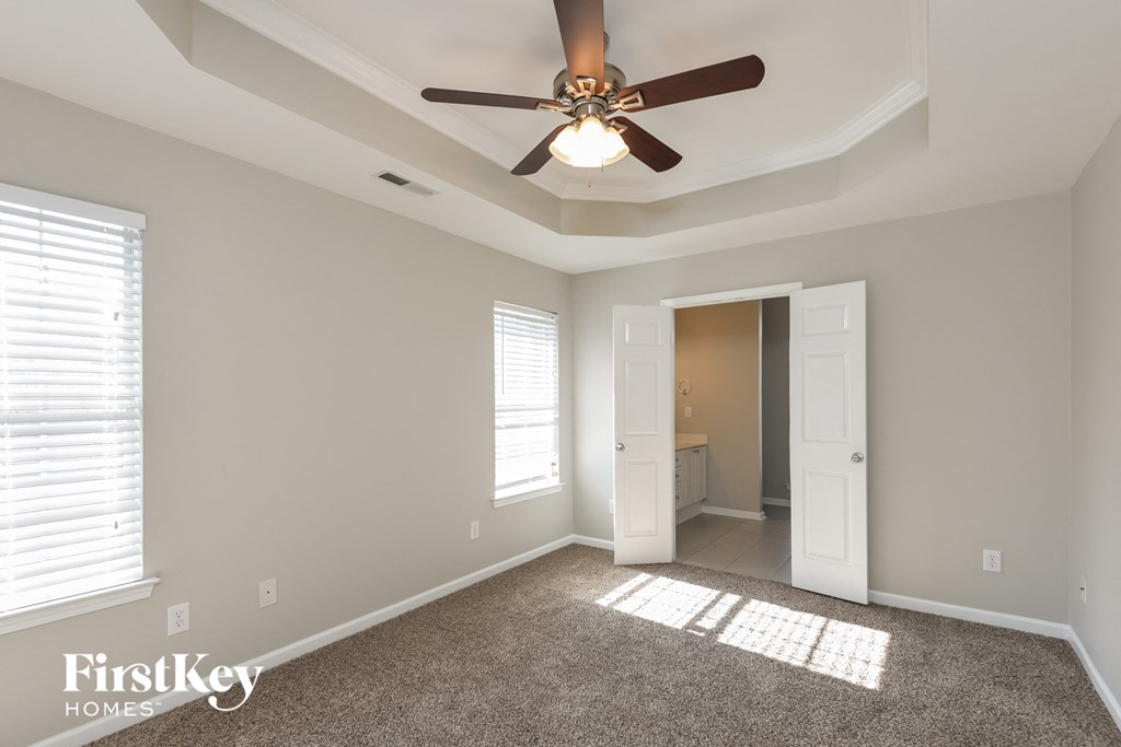 a living room with a ceiling fan and a door to a bathroom