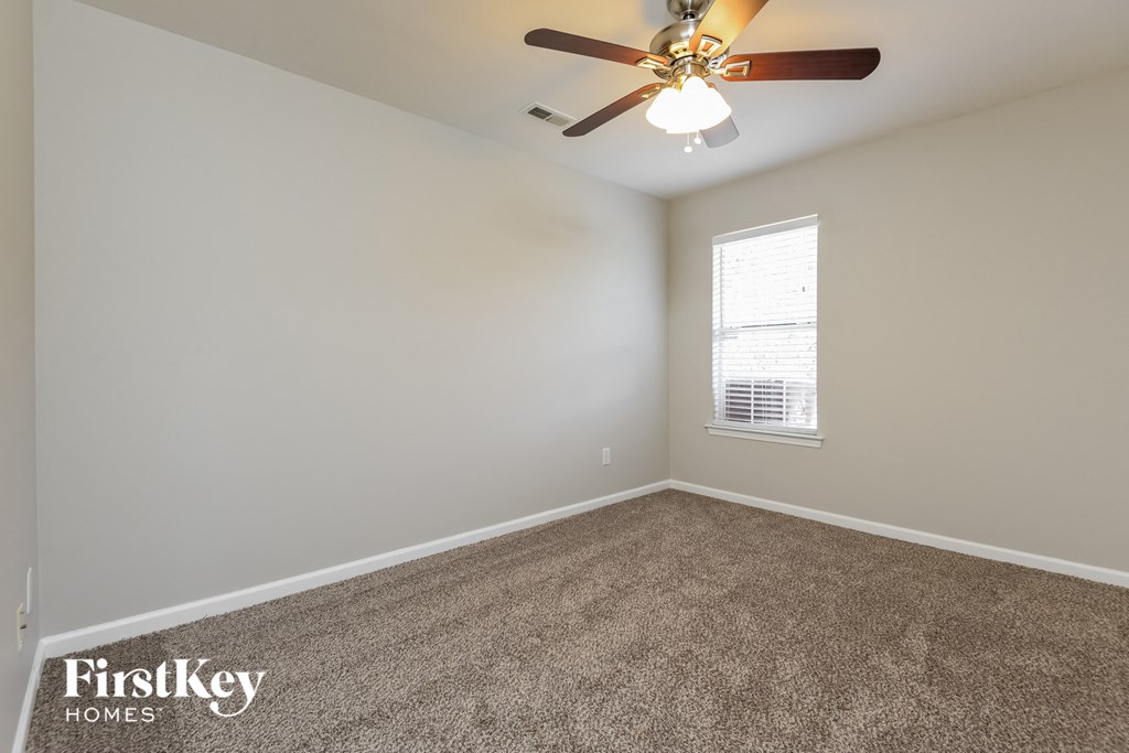 an empty room with a ceiling fan and a window
