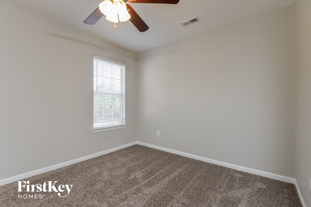 an empty room with a ceiling fan and a window
