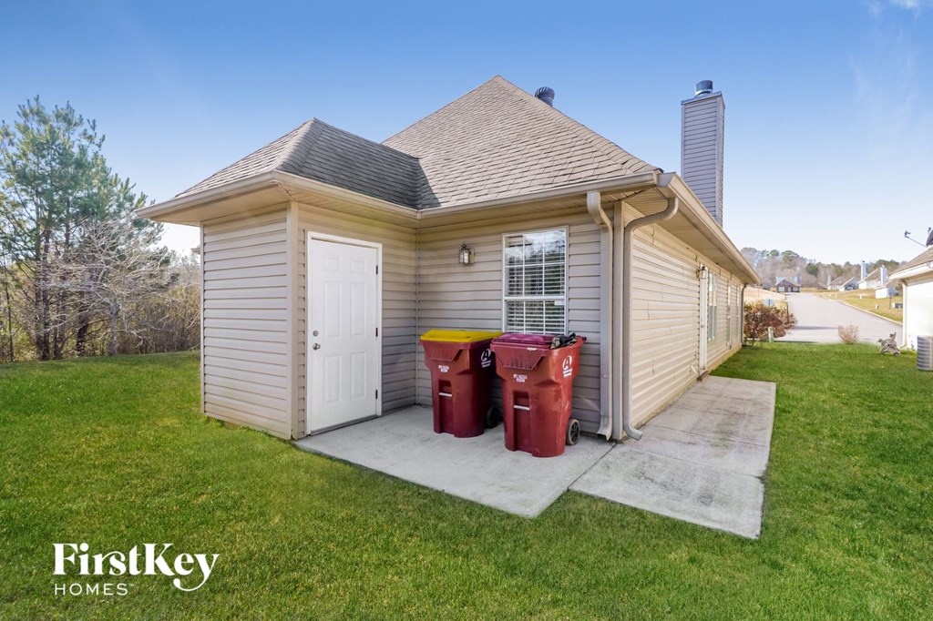 a small tan storage shed with two trash cans in the front