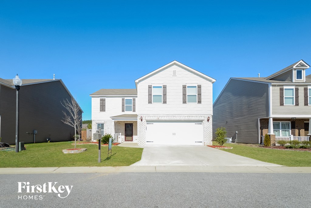 a white house with a white garage door in front of a lawn