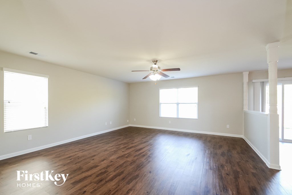 an empty living room with wood floors and a ceiling fan