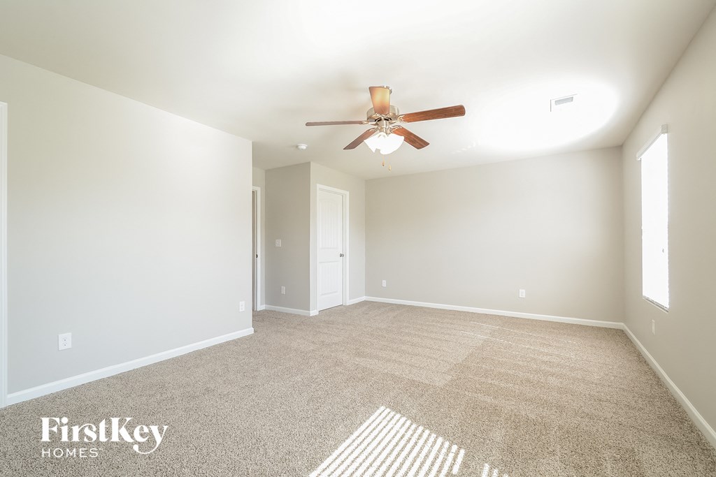 a spacious living room with carpet and a ceiling fan
