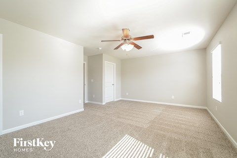 a spacious living room with carpet and a ceiling fan