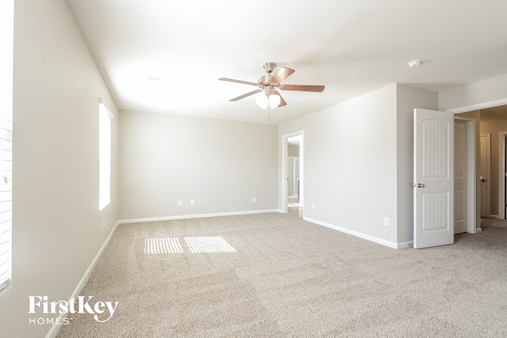 a spacious living room with carpet and a ceiling fan