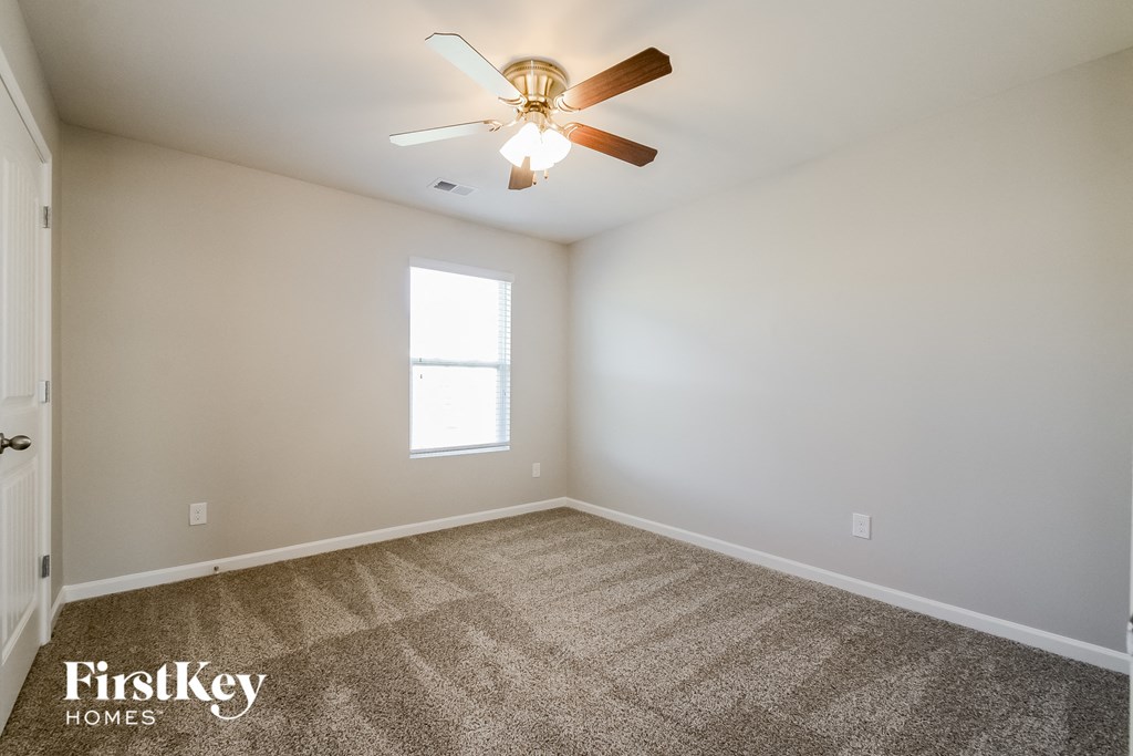 the spacious living room with ceiling fan and carpet
