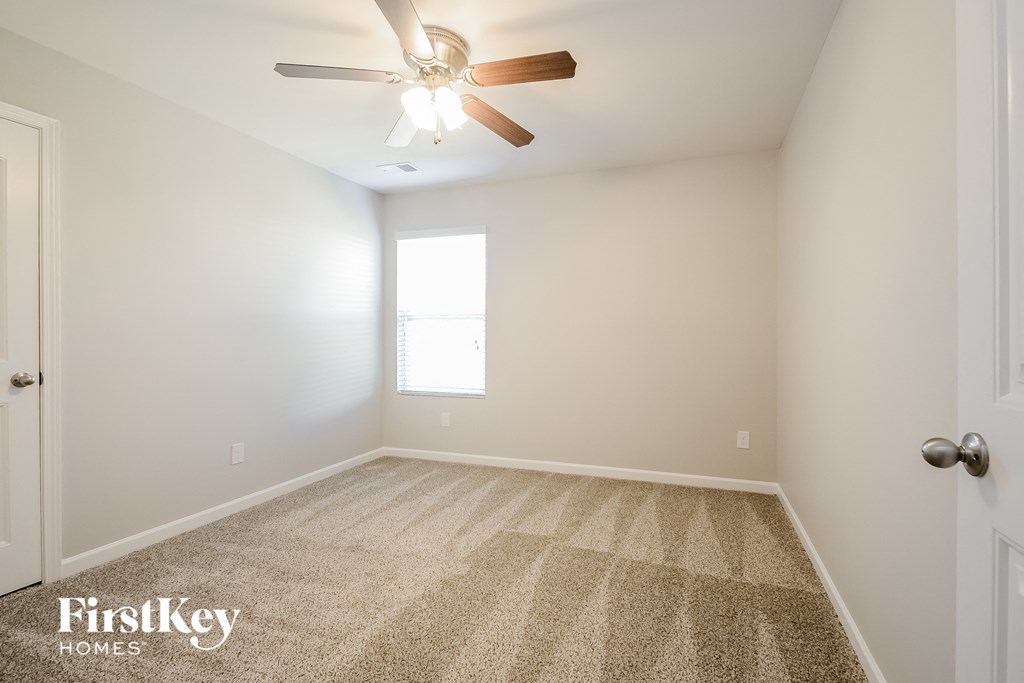 an empty room with a ceiling fan and a window