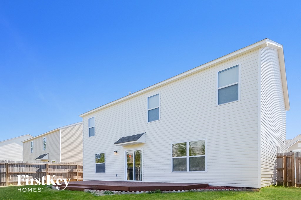 the exterior of a white house with a deck and a blue sky