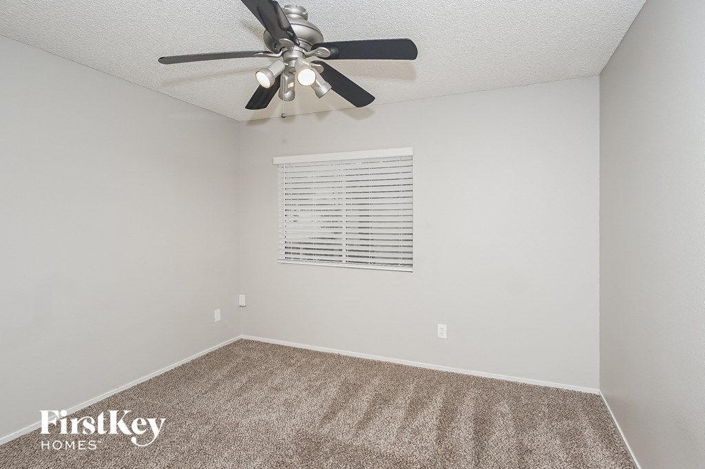 A room with a ceiling fan and a window with blinds.