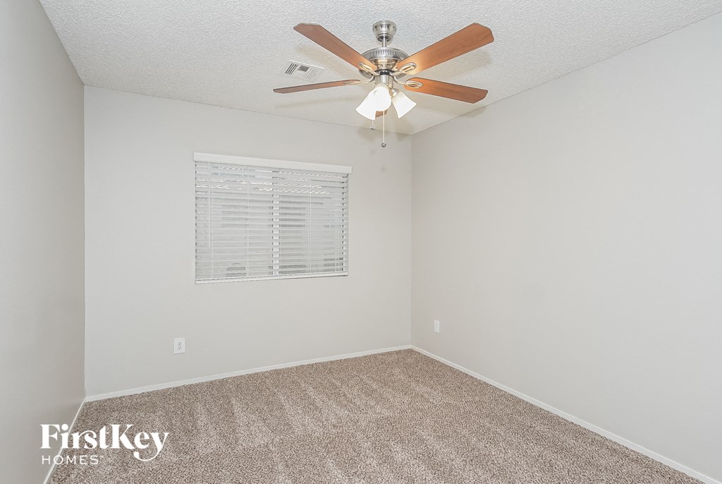A room with a ceiling fan and carpeted floor.