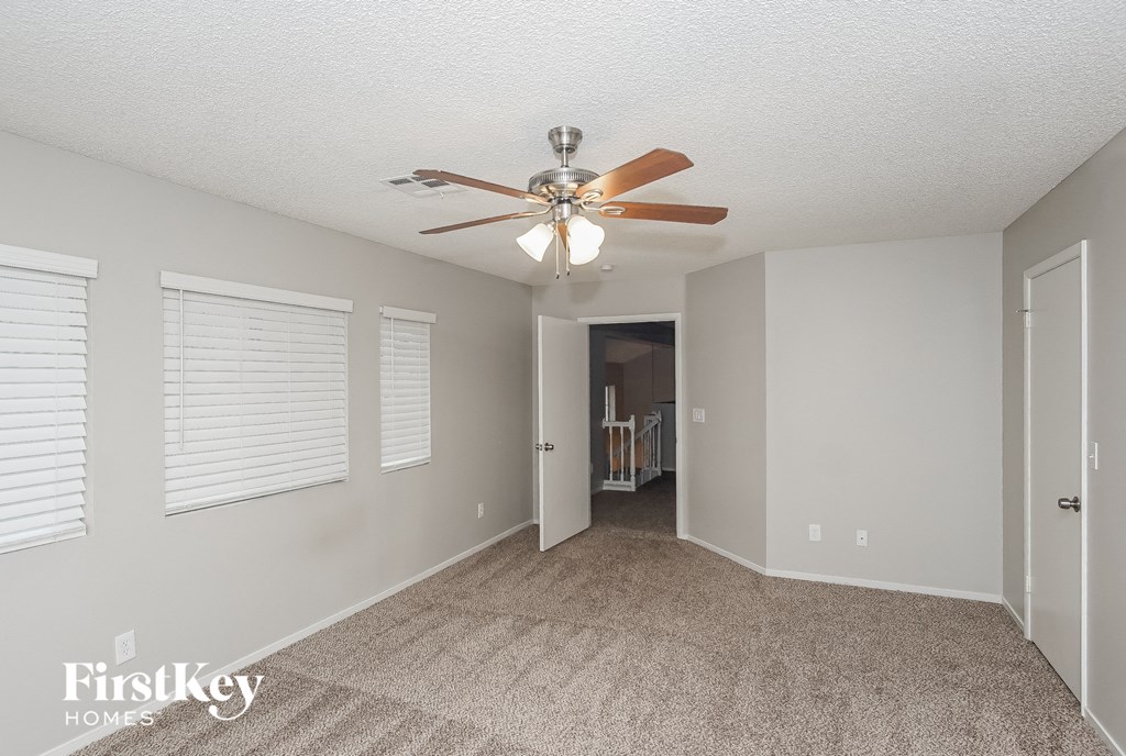 A spacious room with a carpeted floor and a ceiling fan.